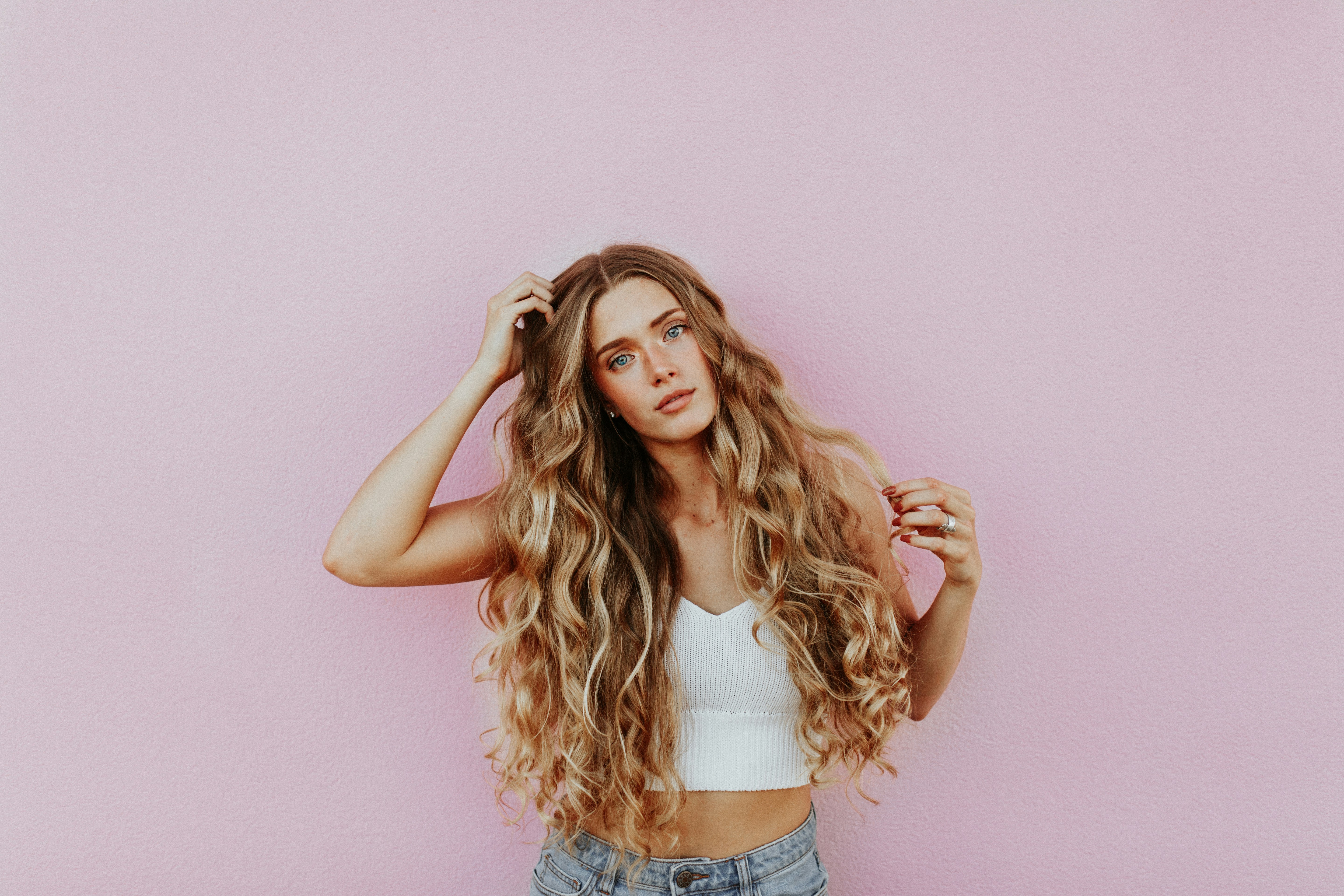 Donna con lunghi capelli biondi mossi su sfondo rosa